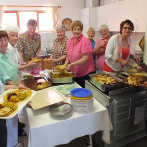 Die groep dames van die NG Vrouediens se Uitreikaksie “in aksie” in die kombuis met die geurige ete 